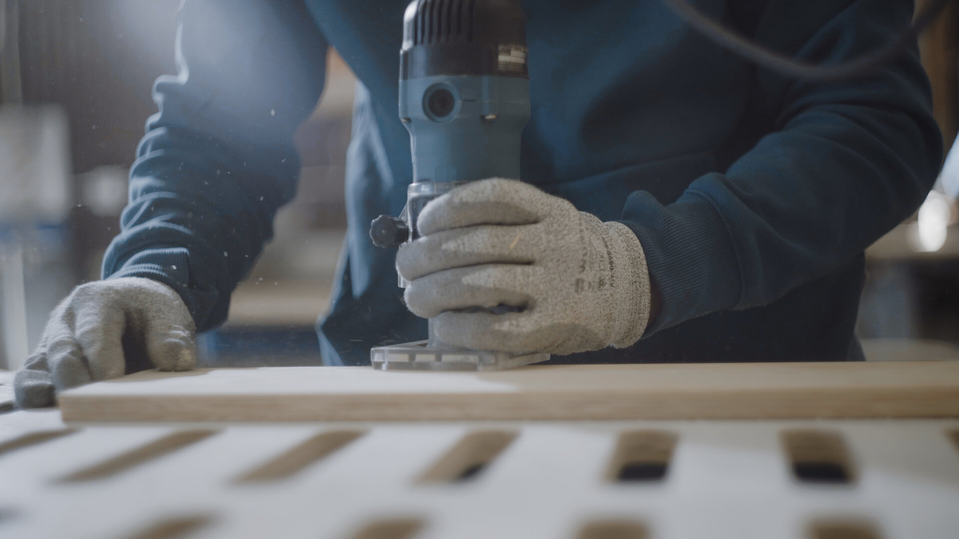 Osoba w rękawicach ochronnych obrabia drewnianą płytę